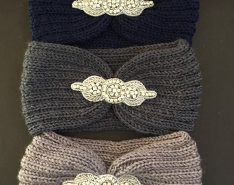 May include: Three knitted headbands with jeweled embellishments. The headbands are in shades of gray, dark gray, and navy blue.