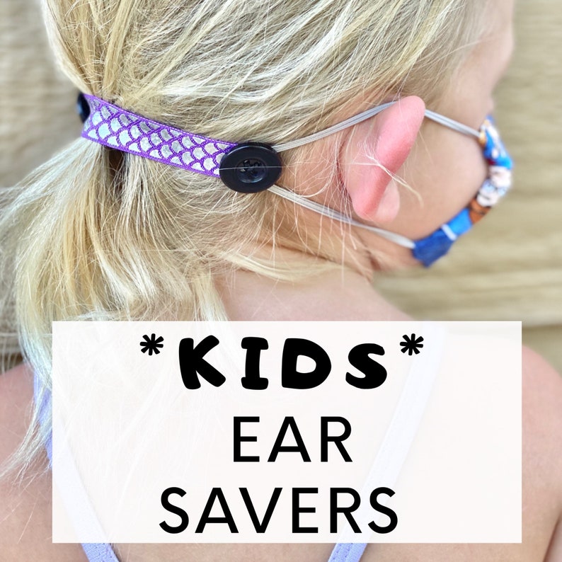 May include: Purple and white patterned fabric ear savers with black buttons. The ear savers are attached to a face mask. The text "*KIDS* EAR SAVERS" is on a white background.