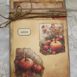 May include: A rustic, brown card with a twine bow. The card has two images of pumpkins and fall leaves. The word "autumn" is written on a label on the card.