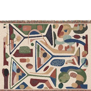 May include: A woven throw blanket featuring a cream-colored background with a repeating abstract pattern of martini glasses in shades of navy blue, forest green, terracotta, and tan, finished with a decorative fringed edge on all four sides.