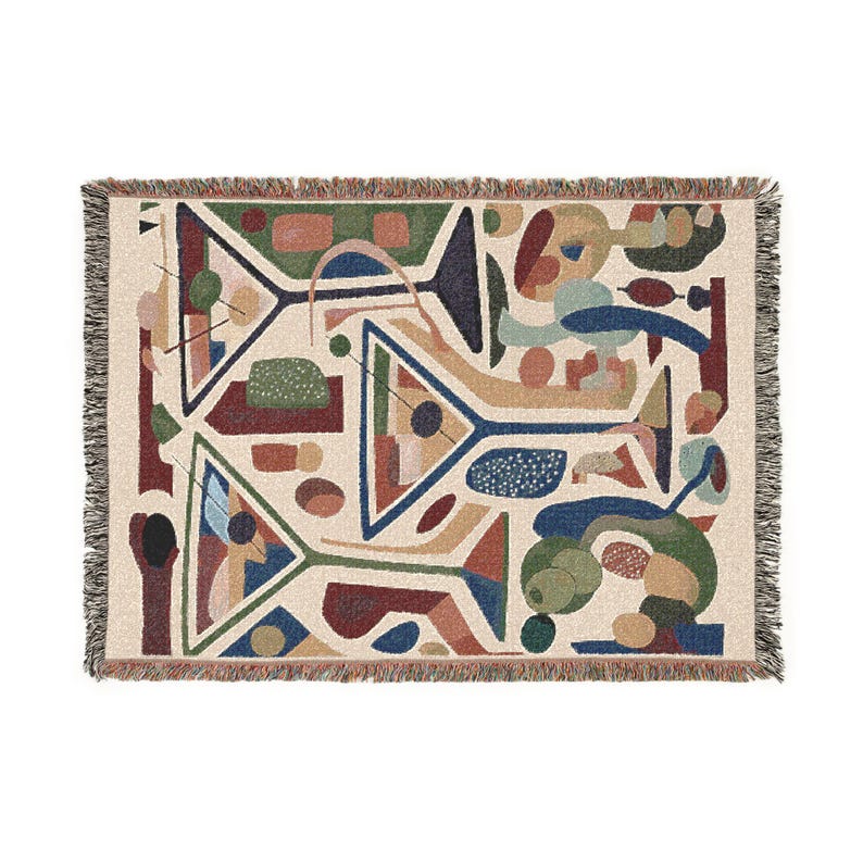 May include: A woven throw blanket featuring a cream-colored background with a repeating abstract pattern of martini glasses in shades of navy blue, forest green, terracotta, and tan, finished with a decorative fringed edge on all four sides.