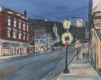 May include: Watercolour painting of a town street at dusk. Buildings line the street, with lit windows and shopfronts. Wreaths with red bows adorn lampposts. A sign reads "Main Street". A star shines in the dark sky.