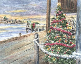 May include: Watercolour painting of a decorated Christmas tree, viewed from a wooden pier. The background shows a coastal scene with a sunset sky and a distant town. A wreath adorns a pier post. The tree has red garland.