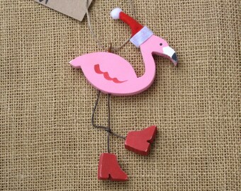 Può includere: Addobbo natalizio a forma di fenicottero rosa in legno con cappello di Babbo Natale rosso e stivali rossi.