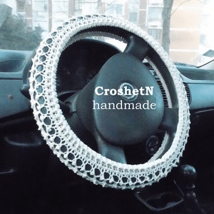 May include: White crocheted steering wheel cover with the text "CroshetN handmade" in black.