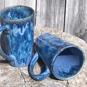 May include: Two blue and white ceramic mugs with a marbled glaze. The mugs have a rounded shape and a handle.