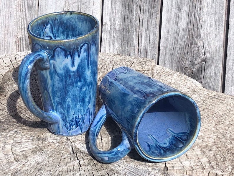 May include: Two blue and white ceramic mugs with a marbled glaze. The mugs have a rounded shape and a handle.