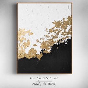 May include: Abstract painting with white and black acrylic paint and gold leaf accents. The painting is framed and ready to hang.