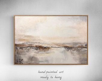 Op de afbeelding: Abstract landschapsschilderij in een houten lijst. Het kunstwerk gebruikt een neutraal palet van beige, bruin en grijstinten. De tekst "hand-painted art ready to hang" staat onderaan de afbeelding.