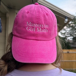 May include: Pink baseball cap with white embroidered text that reads "Masters in Girl Math".