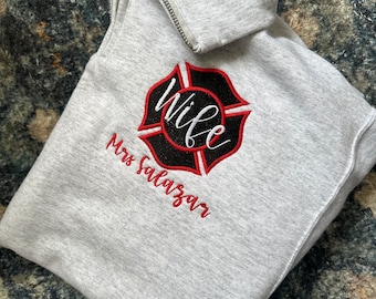 May include: Gray zippered sweatshirt with a black and red firefighter emblem that says "Wife" and "Mrs. Salazar" underneath.