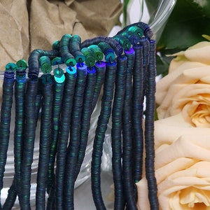 May include: A strand of black and iridescent green sequins, strung together to form a long, thin chain. The sequins are round and have a metallic sheen.