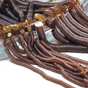 May include: A close-up of a pile of brown and gold metallic sequins. The sequins are arranged in a cascading pattern, with the gold sequins at the top and the brown sequins at the bottom.