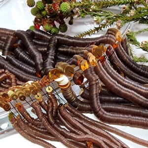 May include: A pile of brown and gold sequins, some are stacked in coils and others are loose. The sequins are shiny and have a metallic finish.