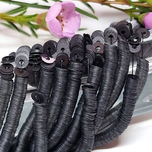 May include: A strand of black sequins, each sequin is a flat circle with a hole in the center. The sequins are strung together on a thin thread.