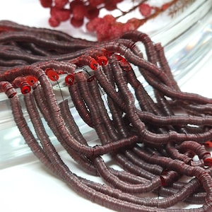 May include: A strand of maroon metallic sequins, each sequin is a small circle with a hole in the center. The sequins are strung together on a thin thread.