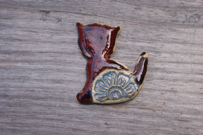 May include: A ceramic cat figurine with a brown glaze and a blue and white floral design on its back.