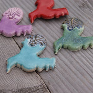 May include: Four ceramic figurines in the shape of birds. The birds are painted in different colors, including purple, red, green, and blue. The birds have detailed designs on their bodies.