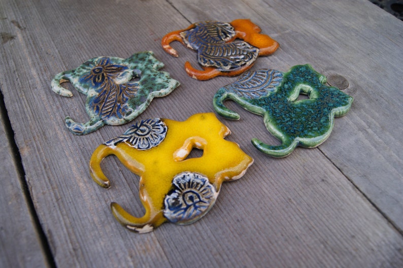 May include: Four ceramic wall hooks in the shape of stylized birds. The hooks are painted in shades of green, yellow, and orange with blue floral designs.