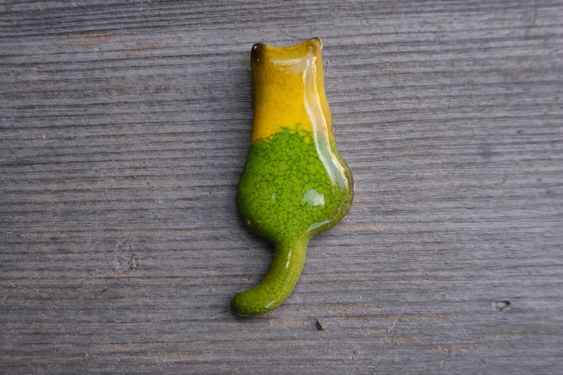 May include: A ceramic cat figurine with a green and yellow glaze. The cat is standing on its hind legs with its tail curled behind it.
