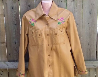 May include: A brown leather jacket with floral embroidery on the collar, cuffs, and pockets. The jacket has a button-up front and a relaxed fit.