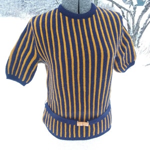 May include: A striped sweater with short sleeves in navy blue and gold. The sweater has a belt with a brown buckle.