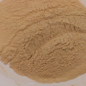 May include: A close-up view of a pile of light brown powder on a white surface.