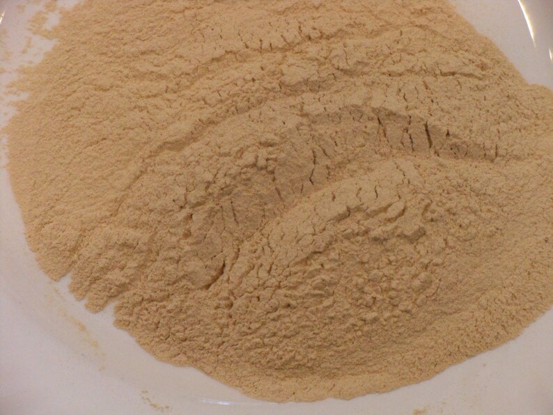 May include: A close-up view of a pile of light brown powder on a white surface.