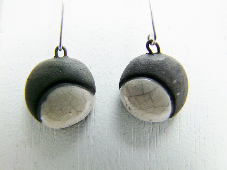 pointed,stuck Ceramic earring white Raku clocked by black.