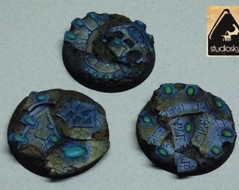 May include: Three round, painted, miniature bases with a stone and green gem design. The bases are for tabletop games like Dungeons and Dragons.