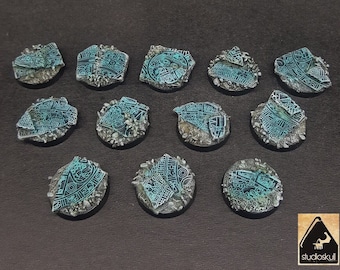 Op de afbeelding: Een verzameling miniatuurterreinbases, elk met een turquoise en zilver kleurenschema. De bases hebben ingewikkelde, gegraveerde ontwerpen en zijn omgeven door een rotsachtige textuur. De bases zijn gerangschikt op een donkere ondergrond.