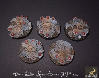 May include: Five 40mm round plastic bases with a grey and brown textured surface. Each base features a different design with intricate details and red accents. The bases are labeled "40mm Eldar Ruins Series (B) 5pcs."