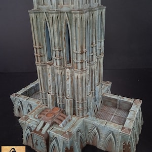May include: A detailed, weathered model of a gothic-style tower with a multi-tiered design. The structure is primarily gray-blue with brown accents, featuring arched windows and a textured surface. The base includes additional architectural elements.