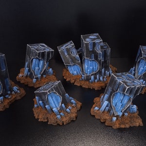 May include: Six miniature, hand-painted, dark gray, crystal-like structures with blue crystals inside. The structures are on a brown, textured base.