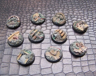 May include: Ten round, brown, plastic bases with various rusted metal details, including pipes, gears, and wires. The bases are designed for miniature wargaming.