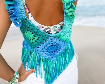 May include: A handmade, blue and green crochet top with ruffled shoulder straps and fringe detailing. The top features a square pattern in the center and a floral design. The color palette includes shades of turquoise, teal, and seafoam green.