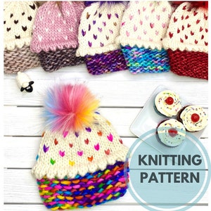 May include: Knitting pattern for a cupcake themed hat with a colorful pom pom. The hat is white with pink hearts and a colorful bottom. The pattern includes the text "Knitting Pattern".