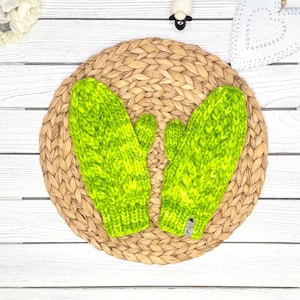 May include: A pair of lime green knitted mittens with a textured pattern. The mittens are on a woven straw placemat.