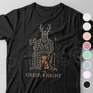 May include: Black t-shirt featuring a graphic of the Green Knight, a figure with antlers and a beard, holding an axe, with a fox at his feet. The text "THE GREEN KNIGHT" is below the illustration. The shirt is displayed with a color selection guide.
