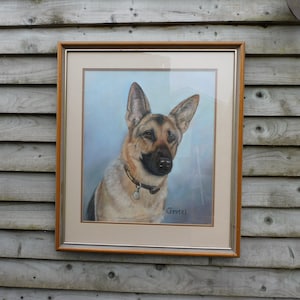 May include: A framed pastel drawing of a German Shepherd dog with a brown and black coat. The dog is wearing a silver collar with a tag. The drawing is signed "Gretzel" in the bottom right corner.