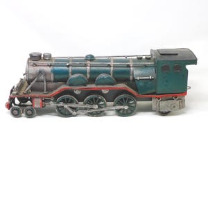 Könnte beinhalten: Ein detailliertes Modell einer Lokomotive in Türkis, Silber und Grün. Der Zug hat sechs Räder, einen detaillierten Motor und rote Akzente. Das Modell ist ein dekoratives Objekt, wahrscheinlich für die Ausstellung oder Sammlung.