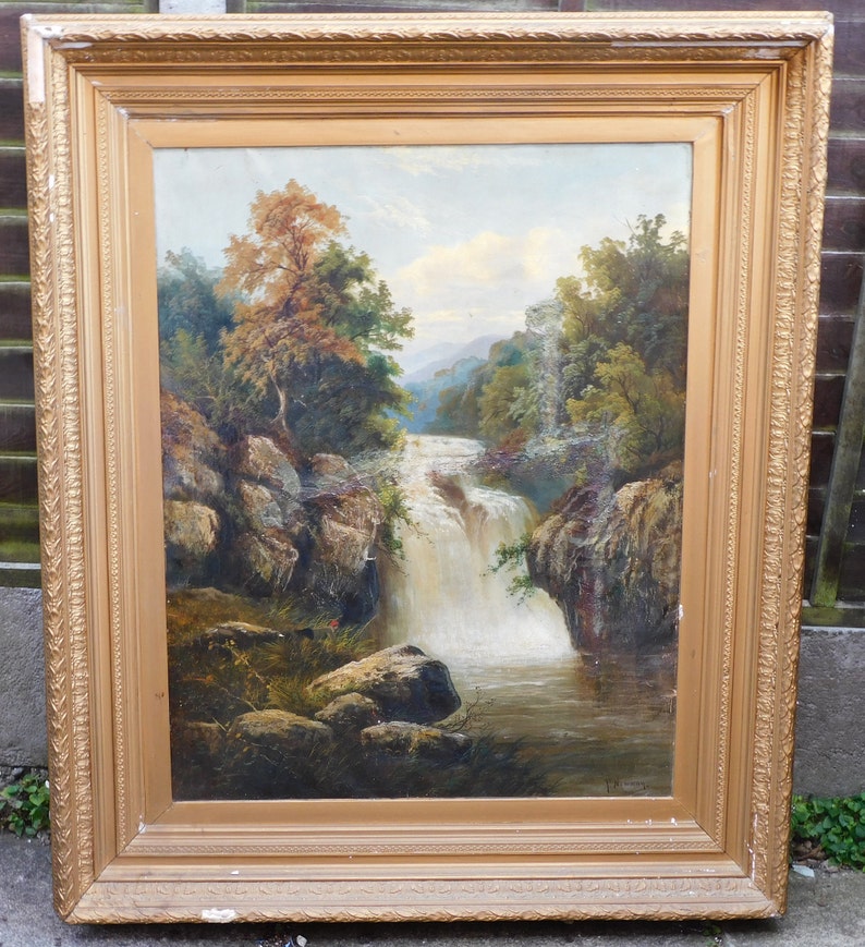 May include: A framed oil painting depicting a waterfall cascading through a rocky landscape. Lush green trees and foliage surround the waterfall, creating a serene and picturesque scene.