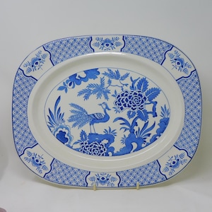 Könnte beinhalten: Eine ovale Servierplatte mit blauem und weißem Blumendesign. Die Mitte zeigt ein Vogel- und Blumenmotiv, umgeben von einem gemusterten Rand. Ein klassisches Geschirrstück.