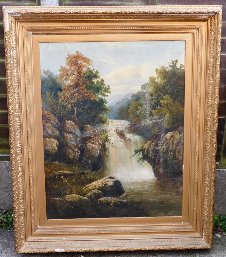 May include: A framed oil painting depicting a waterfall cascading through a rocky landscape. Lush green trees and foliage surround the waterfall, creating a serene and picturesque scene.