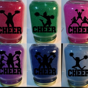 Pu&ograve; includere: Sei barattoli di vetro con glitter all'interno e una silhouette nera di cheerleader con la parola "CHEER" stampata sul davanti. I barattoli sono di diversi colori: rosso, verde, rosa, viola, blu e azzurro.
