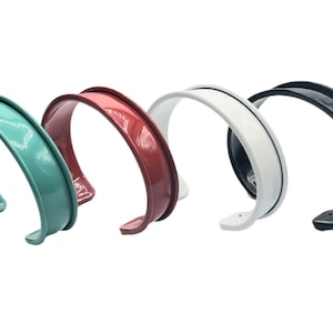 May include: Four different colored metal bracelets. The bracelets are all the same size and shape, but they are different colors: teal, red, white, and black.