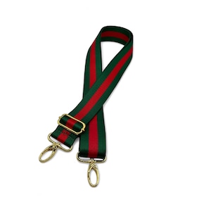 May include: A green and red striped adjustable strap with gold hardware. The strap is made of a woven fabric and has a classic design.