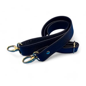 May include: A black leather shoulder strap with gold hardware and two swivel clasps.