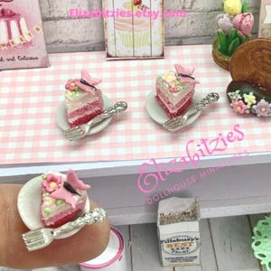 May include: Three miniature pink and white layered cakes with butterfly toppers on white plates with silver forks. The cakes are on a pink and white checkered tablecloth.