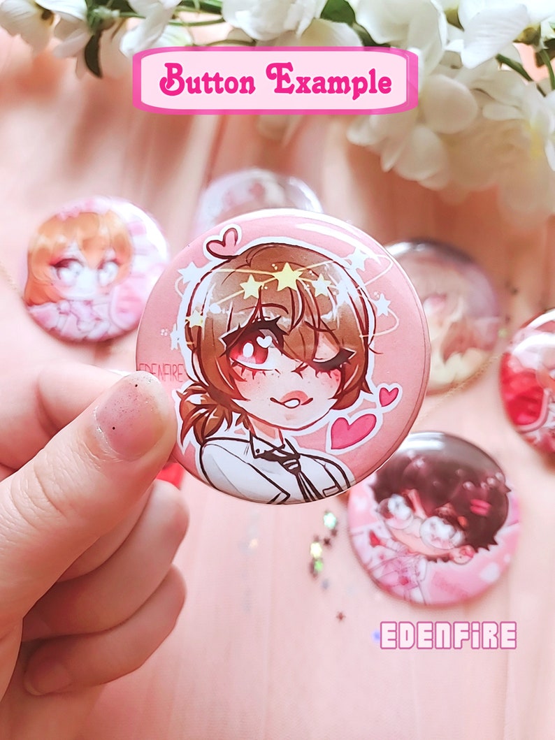 Op de afbeelding: Een roze knoop met een cartoonillustratie van een persoon met bruin haar, die een wit shirt en een zwarte stropdas draagt. De persoon heeft sterren en harten rond zijn hoofd. De knoop heeft de tekst "EDENFIRE" erop.